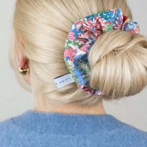 Frau mit blondem Dutt und buntem Blumen-Muster Scrunchie