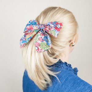 Frau mit blondem Pferdeschwanz und bunter Blumen-Muster Haarschleife